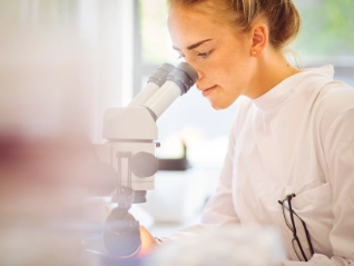 Young female pharmaceutical worker with microscope