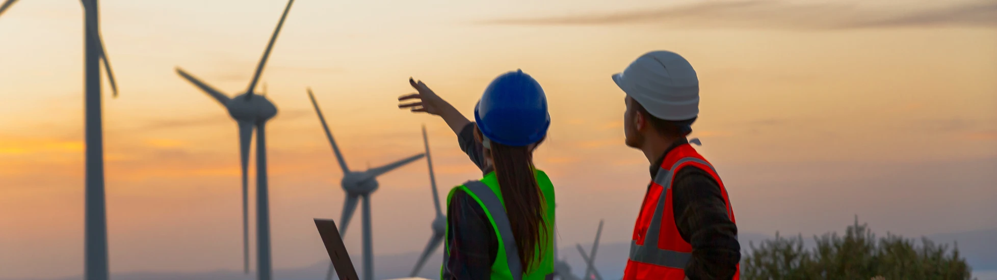 Two energy workers in front of wind turbines