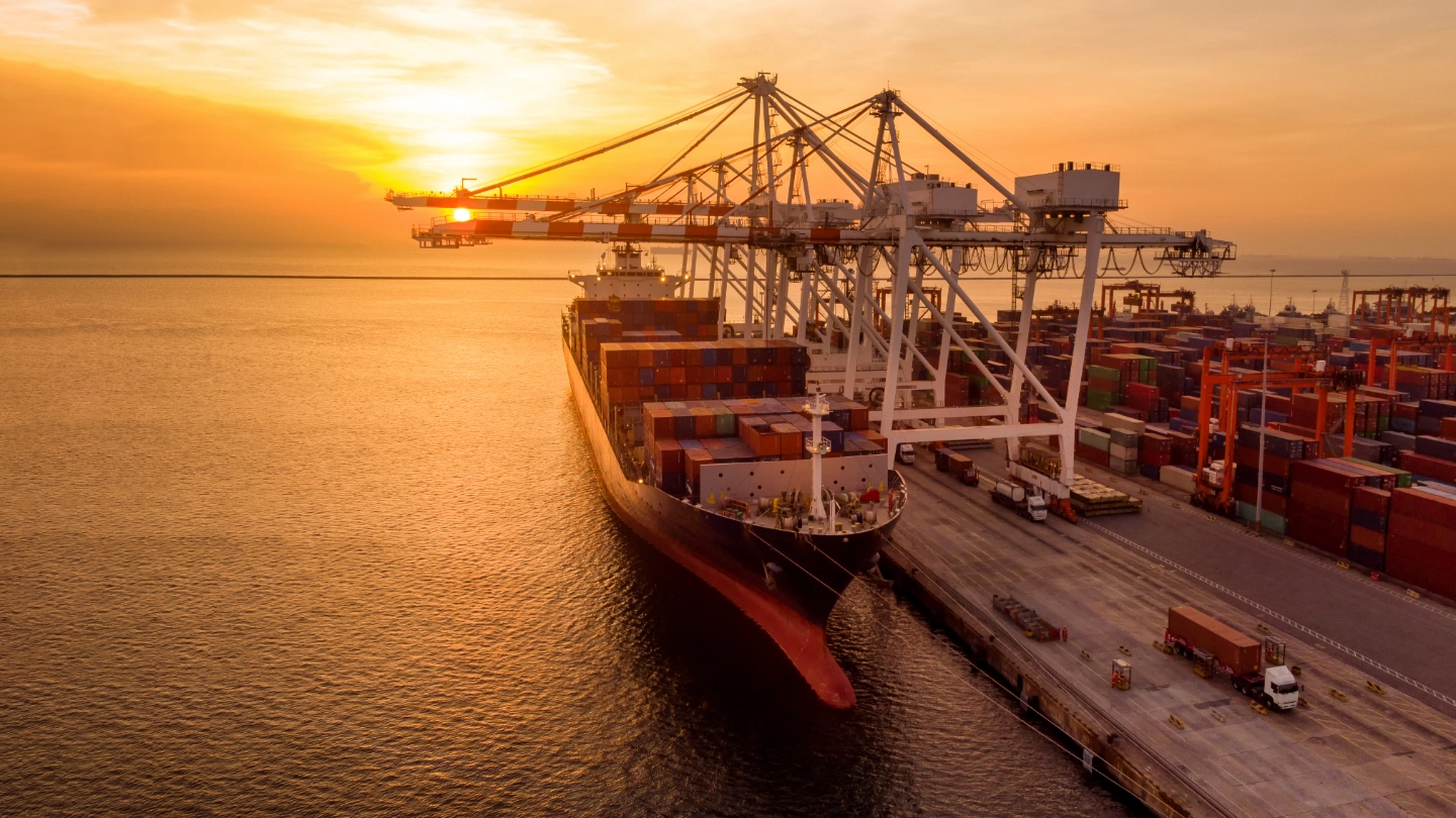 container-ship-in-port-at-sunset Crane loading container onto container ship at sunset